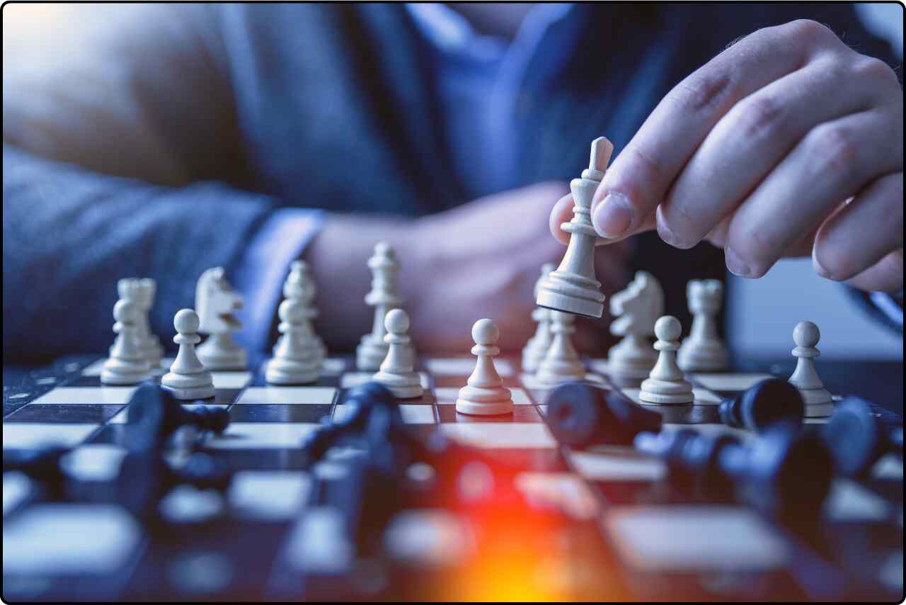 Close-up of a person making a move on a chessboard, with their hand poised over a chess piece.